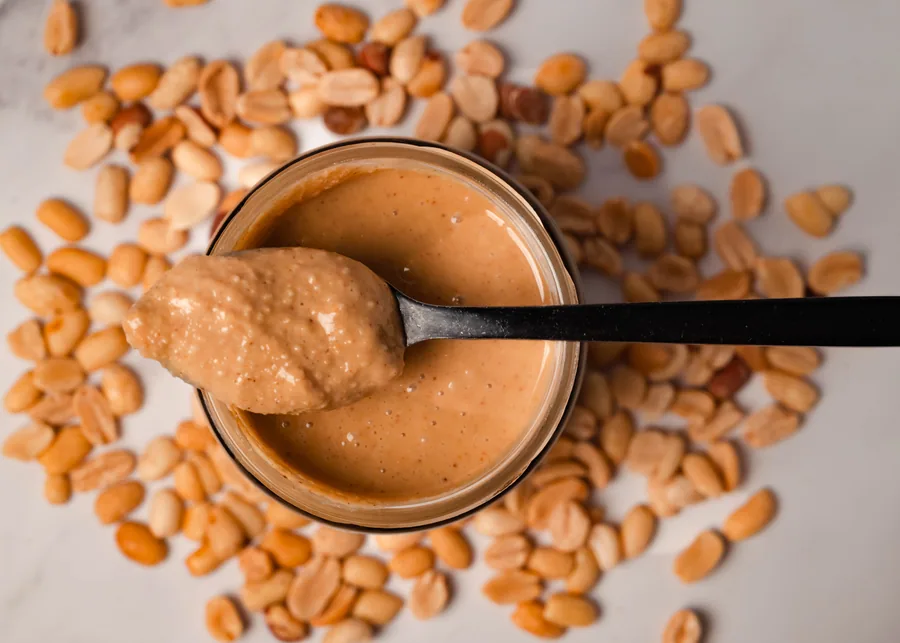 Crema de cacahuate Speanut en una cuchara, sobre cacahuates tostados